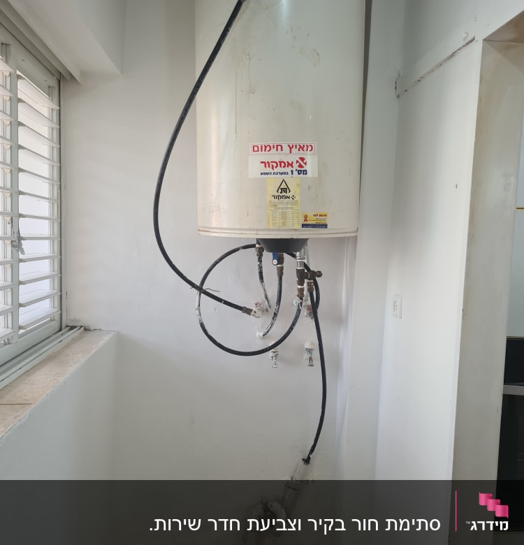 דוד חימום עם צינורות וחיבורים על קיר לבן